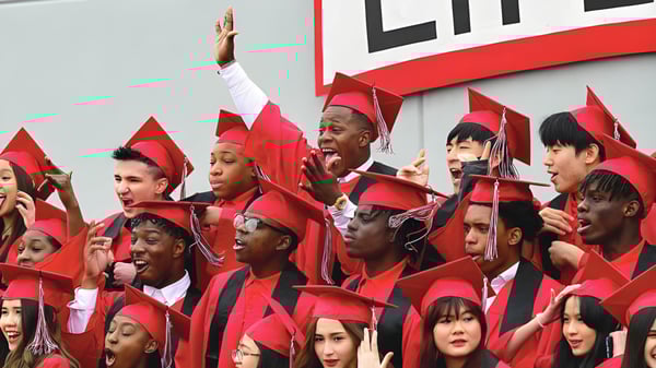 Las graduadas y graduados de la Life Prep Academy celebran frente a un gran cartel de LIFE sus éxitos académicos.