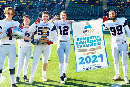 Estudiantes de la Lillian Osborne High School están en el campo de deporte sosteniendo un banner para los campeones de fútbol americano 2021.