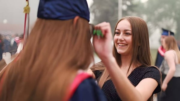 Una estudiante de la Lillian Osborne High School conversa riendo con otra persona en el animado espacio exterior de la escuela.