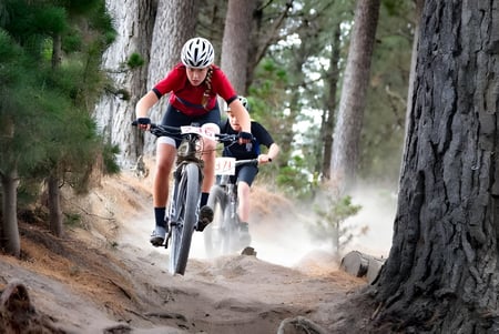 Un estudiante de la Lincoln High School monta en bicicleta con una camiseta roja por un camino en el bosque.