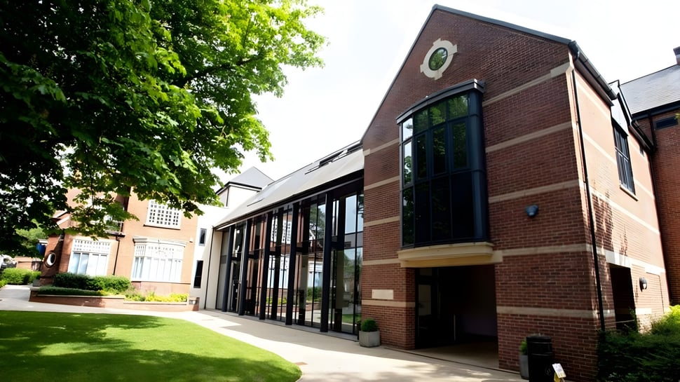 El edificio de ladrillo de la Lincoln Minster School se encuentra frente a un prado verde y está rodeado de árboles.
