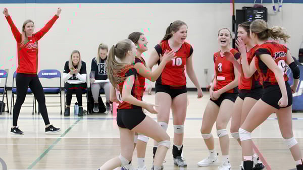 Estudiantes de la Lindsay Thurber Comprehensive High School celebran juntas en el campo de voleibol durante un partido.