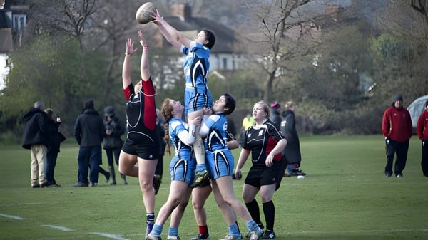 Un grupo de estudiantes juega rugby en el campo del Llandovery College frente a espectadores.