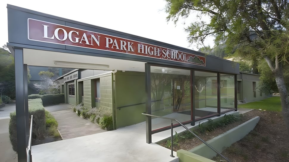 La vista exterior de Logan Park High School con entrada señalizada y área verde diseñada en primer plano.