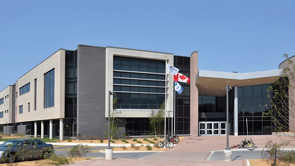 El moderno edificio de varios pisos de la Longfields-Davidson Heights Secondary School con una bandera canadiense y bicicletas en primer plano.