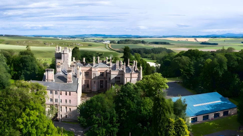 Un castillo de aspecto medieval rodeado de colinas y paisajes boscosos en el terreno de la Longridge Towers School.