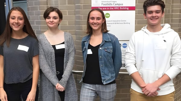 Cuatro estudiantes están frente al edificio con el letrero Facilities Campus en el campus de la Lord Beaverbrook High School.