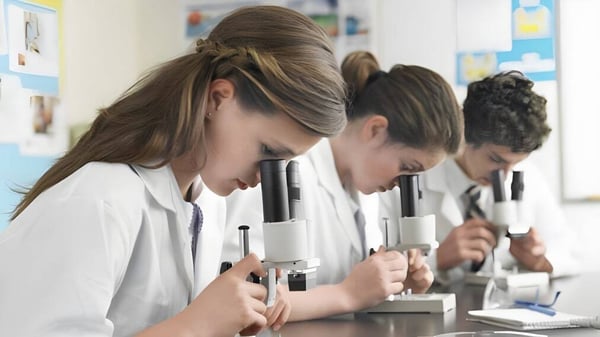 Estudiantes de la Lord Tweedsmuir Secondary School trabajan concentrados con microscopios en la clase de ciencias.