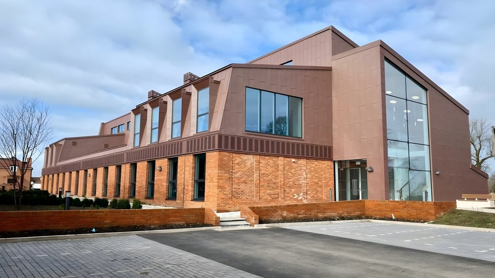 El moderno edificio principal de varios pisos del Lord Wandsworth College, con fachada de ladrillo y vidrio, está rodeado de un camino pavimentado y jardines.