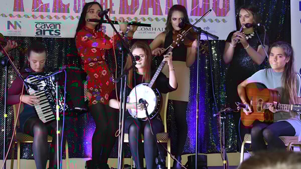 Un grupo de músicos y músicas del Loreto College Cavan se presenta en el escenario con luces de colores.