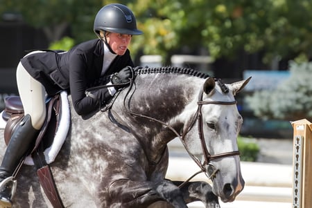 Una estudiante del Loreto College Mullingar monta un caballo gris al aire libre.
