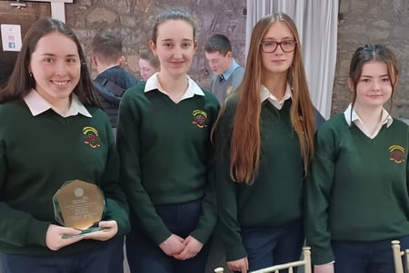 Un grupo de alumnas y alumnos en uniforme escolar verde está frente a un edificio de piedra en el campus de la Loreto Secondary School en Cork.