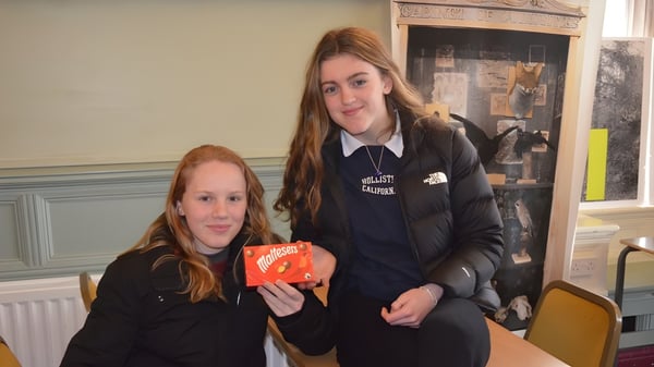 Dos alumnas de la Loreto Abbey Secondary School están juntas en un aula con chimenea.