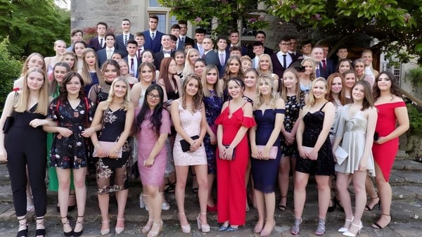 Un grupo de estudiantes vestidos formalmente frente a una construcción de piedra en el campus de la Loretto School.