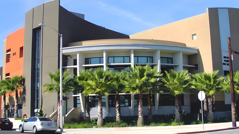 Edificio moderno de varios pisos con fachada curva y palmeras en el terreno del Los Angeles Unified School District.