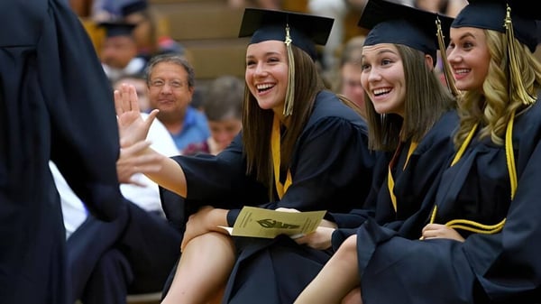 Un grupo de jóvenes mujeres en vestimenta de graduación celebra su éxito en el Loyalist Collegiate & Vocational Institute.