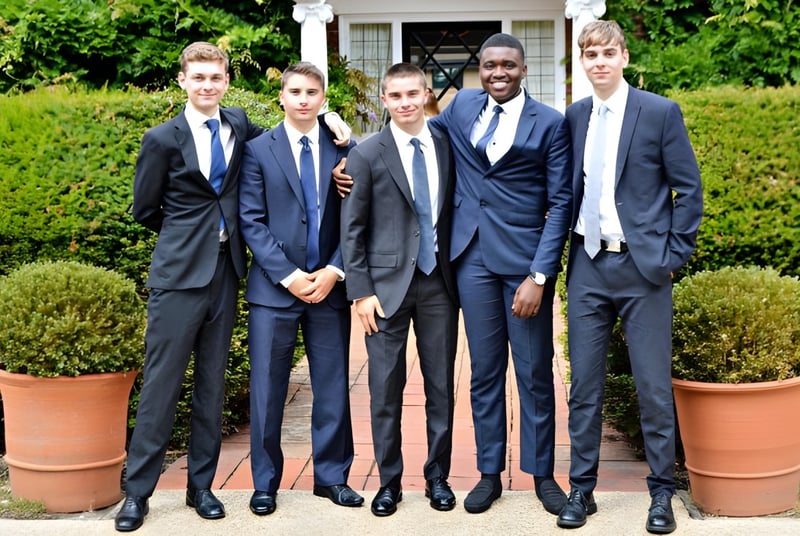 Un grupo de estudiantes de la Luckley House School está vestido formalmente en un jardín bien cuidado con plantas en macetas y setos.