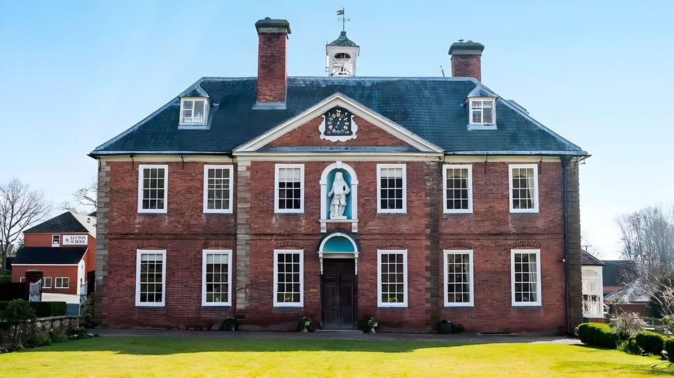 El histórico edificio de la Lucton School se encuentra en un área verde bien cuidada y está rodeado de árboles.