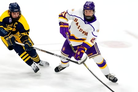 Dos jugadores de hockey completamente equipados juegan en el campo de hielo de Luther College High School.