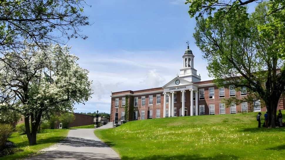 El histórico edificio principal se encuentra en el verde campus del Lyndon Institute con un camino sinuoso delante.