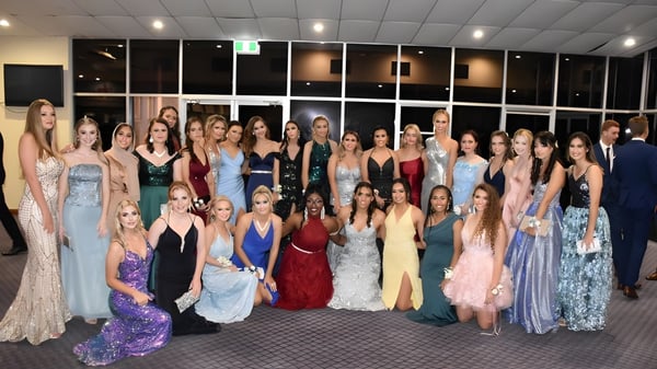 Un grupo de estudiantes de la Mabel Park State High School posan en un evento escolar formal en vestidos de noche.