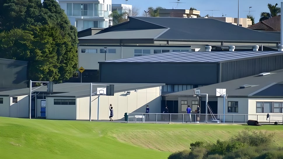 El moderno edificio de varios pisos del Macleans College con techo a dos aguas y grandes ventanas está rodeado de áreas verdes.