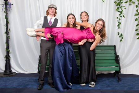 Un grupo de cuatro personas con ropa formal se encuentra frente a un fondo verde en el terreno de Mahurangi College.