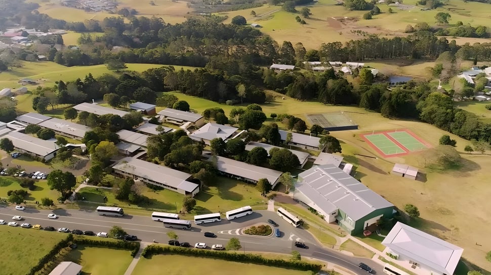 La imagen aérea muestra la instalación deportiva y los edificios de la Maleny State High School en un entorno rural con colinas y bosques.