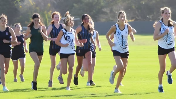 Un grupo de jóvenes atletas entrena juntos en el campo de deportes del Manawatu College.