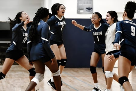 Jugadoras de voleibol de la Mannahouse Christian Academy celebran juntas en la cancha.
