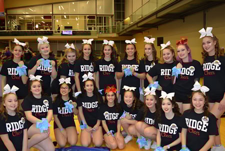 Un grupo de estudiantes de la Maple Ridge Secondary School con camisetas negras y orejas de conejo posan en un gimnasio.