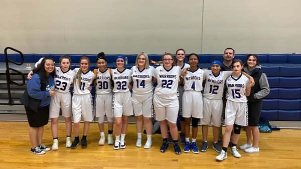 Un grupo de jóvenes jugadoras de baloncesto está reunido en la cancha de baloncesto de la Maranatha Baptist Academy.