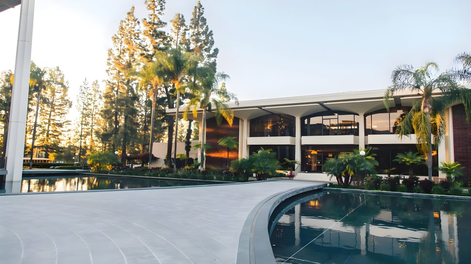 El moderno campus de varios pisos de la Maranatha High School con un patio cubierto y una piscina en primer plano.