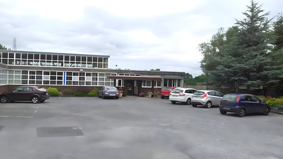 Edificio de varios pisos del Marist College con estacionamiento y árboles bajo un cielo nublado.