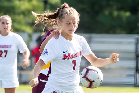 Una joven futbolista con camiseta blanca y el número 7 corre en el campo del Marist College.
