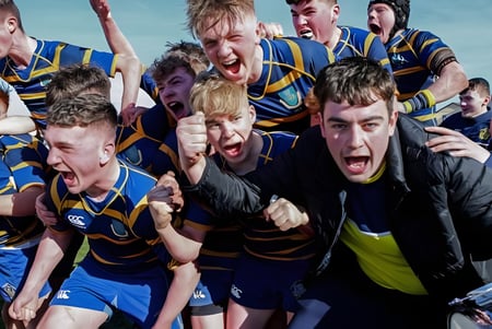 Un grupo de jugadores de rugby del Marist College celebra en el campo después de un partido.