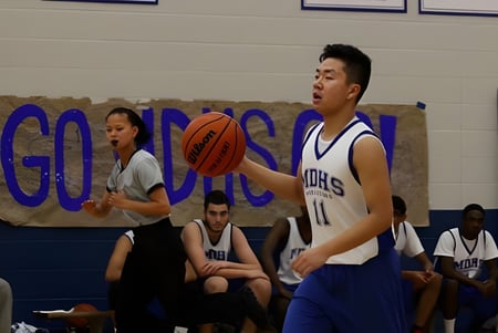 Dos jugadores de baloncesto de la Markham District High School luchan por el balón durante un partido en la cancha.