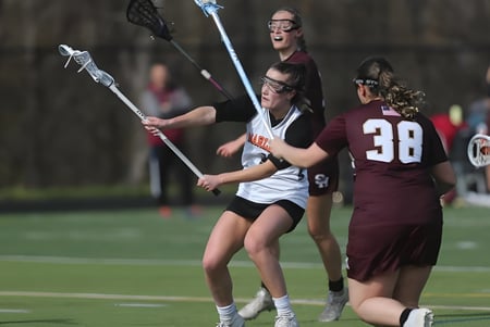 Estudiantes de Marlborough Girls juegan un partido de lacrosse en un campo cubierto de hierba.