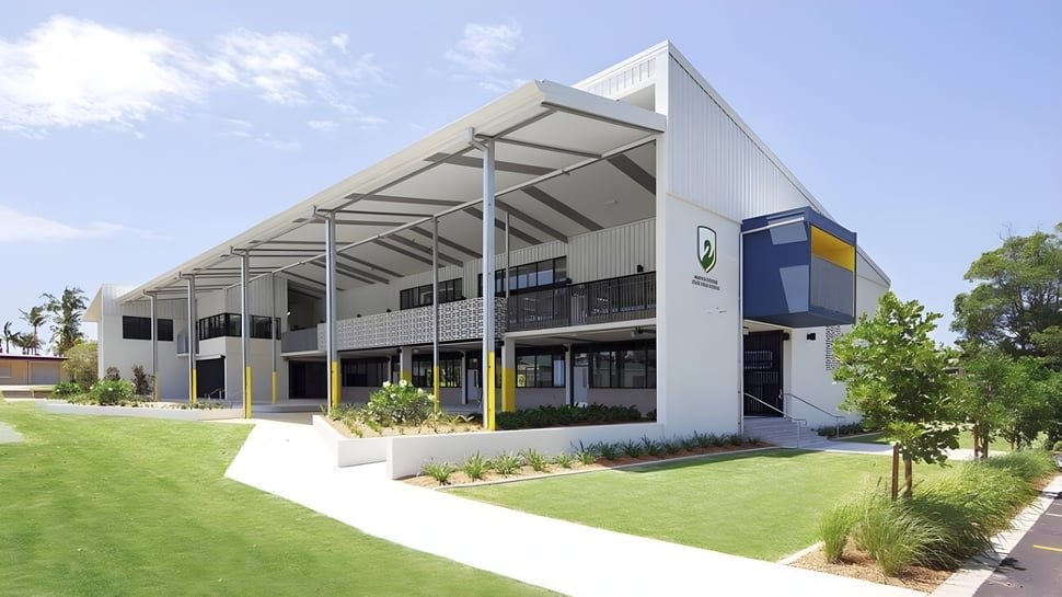 El moderno edificio principal de la Maroochydore State High School con césped cuidado y un entorno verde.