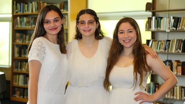 Tres alumnas con cabello largo y oscuro posan juntas en la biblioteca de The Marvelwood School.