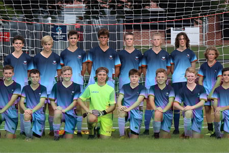 Estudiantes de la Maryborough State High School posan juntos frente a una portería de fútbol en un campo de césped.