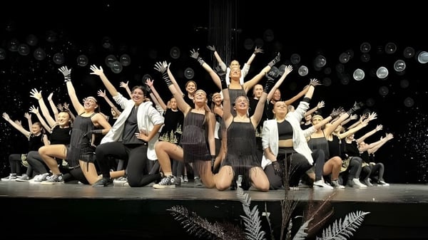 Un grupo de bailarines de la Massey-Vanier High School realiza una actuación en un escenario con focos.