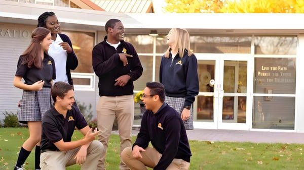 Estudiantes de la Maur Hill-Mount Academy están frente a un edificio con el letrero Graduación y conversan en un área verde.