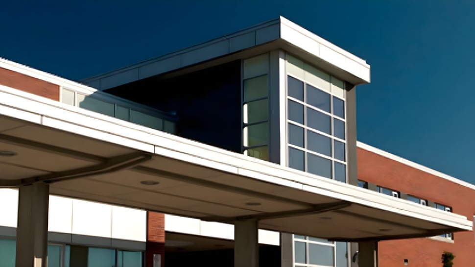 El moderno edificio de varios pisos de la Maxwell Heights Secondary School con fachada de vidrio y ladrillo bajo un cielo azul claro.