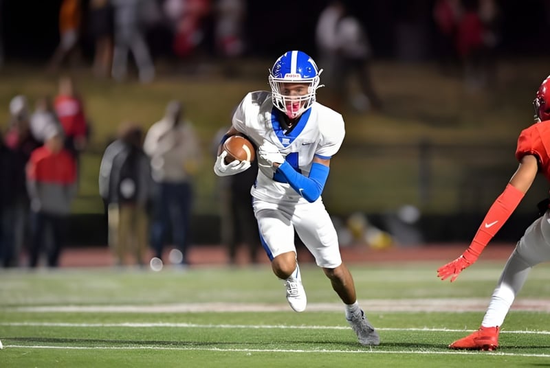 Un jugador de fútbol americano en uniforme blanco con acentos azules corre con el balón en el campo de fútbol americano de la McCallie School.