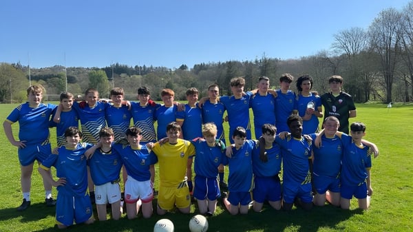 Un grupo de jóvenes futbolistas del McEgan College está en un campo de césped con árboles de fondo.