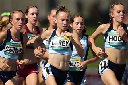 Un grupo de estudiantes femeninas de la Menai High School corre en una competición en la pista de atletismo.