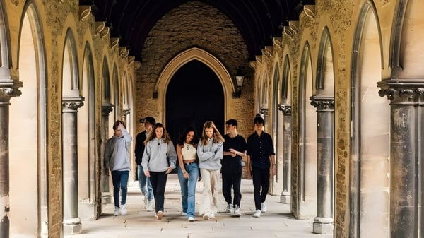 Un grupo de estudiantes camina a través del elegante pasillo arqueado de la Mercy Secondary School.