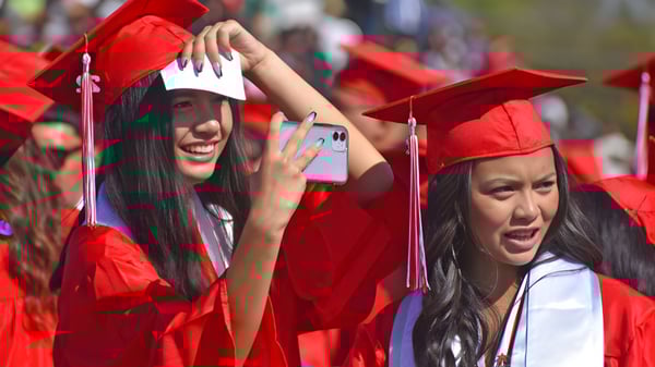 Dos estudiantes de la Mercy Secondary School Ballymahon celebran su fiesta de graduación al aire libre con togas rojas.