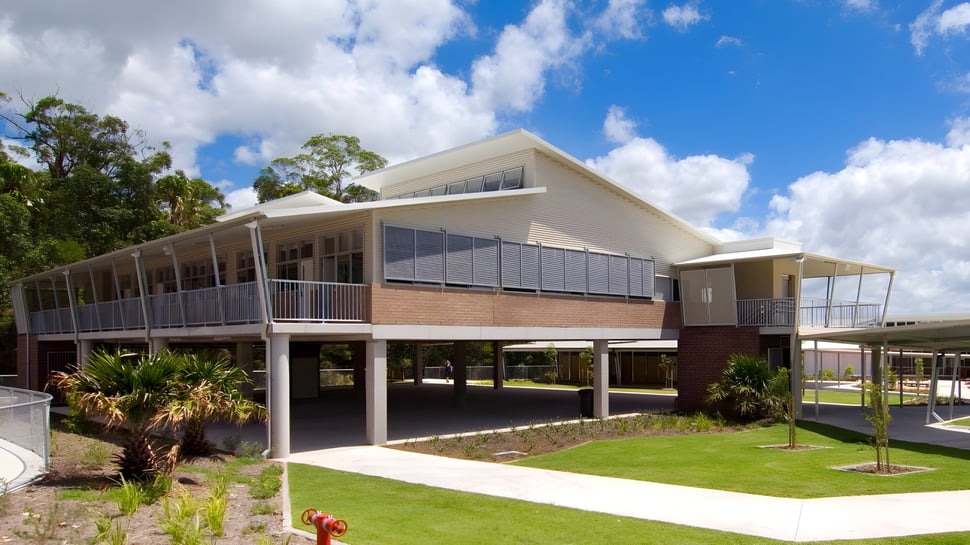 El moderno edificio de dos pisos del Meridan State College está rodeado de palmeras y hierba verde.